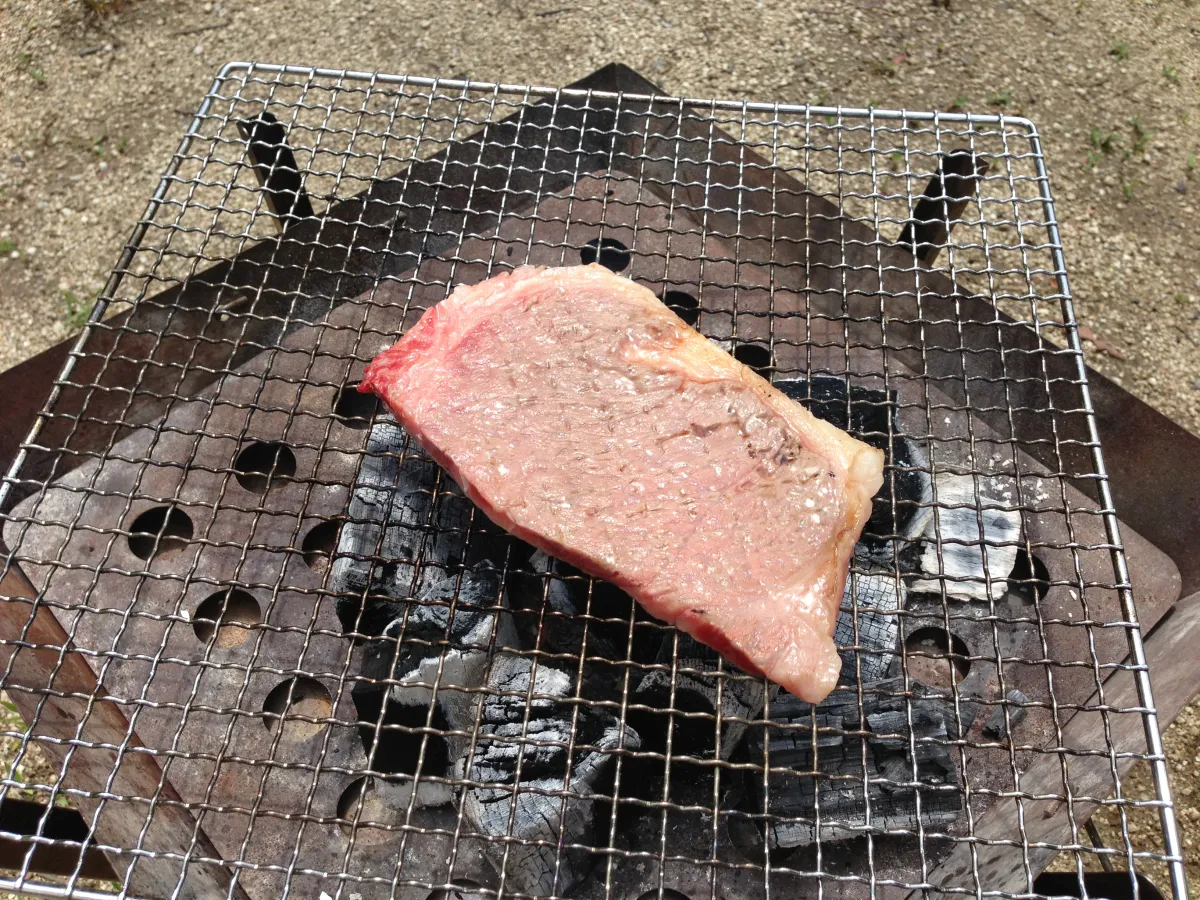 ユニフレーム ファイアグリルでステーキを焼く様子